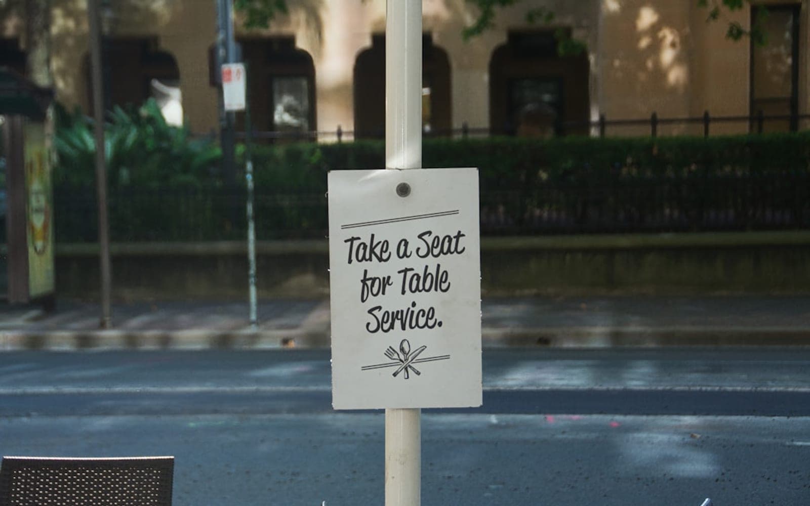 Sign reads take a seat for table service.