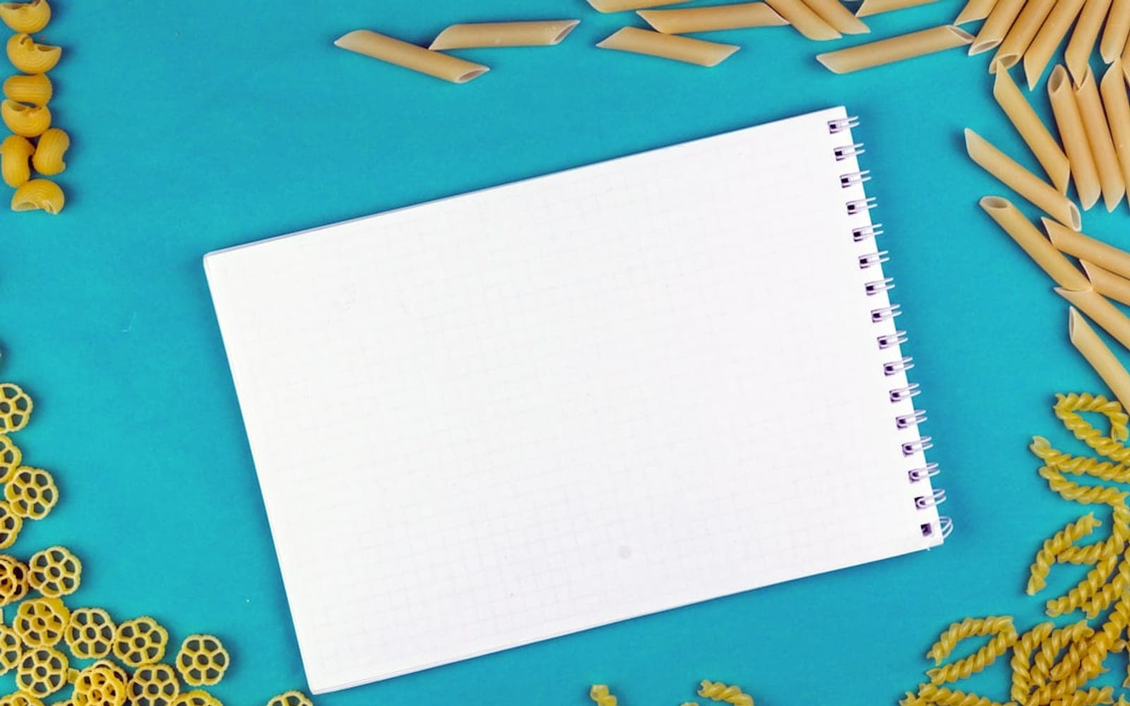 a notebook surrounded by pasta noodles and other items